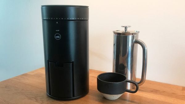 Wilfa Uniform WSFBS 100B coffee grinder on kitchen table with a coffee cup and french press
